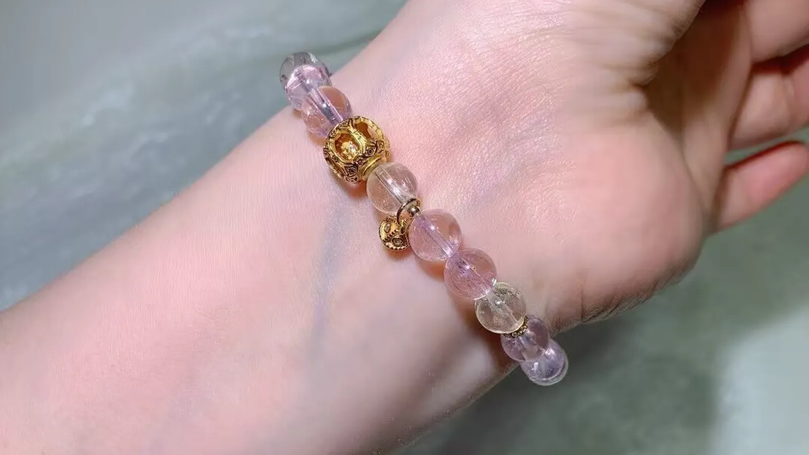 手腕上的猫眼紫锂辉手链:淡粉到淡紫的珠子,配古法饰品