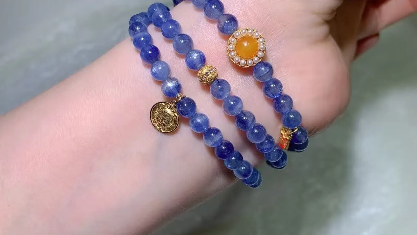 绕在手腕上的天然蓝晶石多圈手链,深浅蓝色条纹珠配蜜黄色蛋面和古法圆牌吊坠